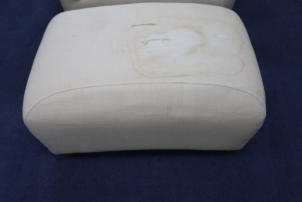 A contemporary upholstered club armchair and foot stool